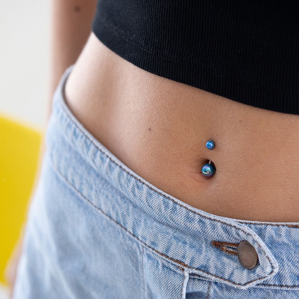 Navlepiercing med metalliske kugler