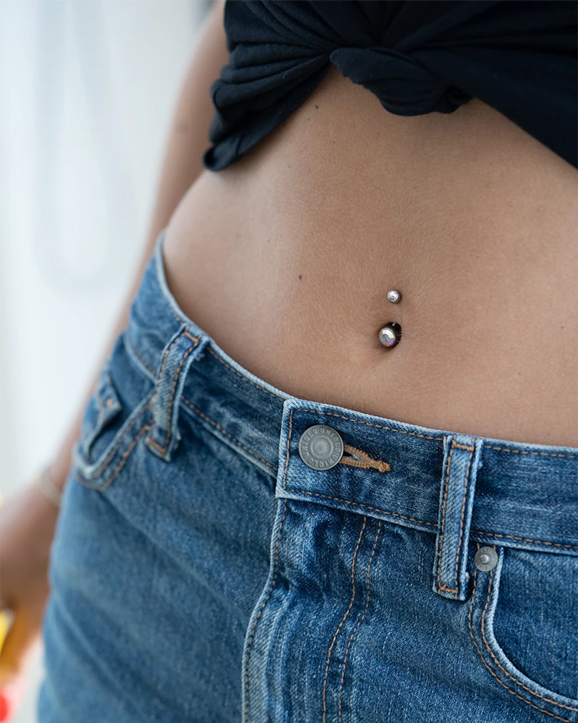 Navlepiercing af titanium med to sten